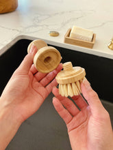 Load image into Gallery viewer, View of two white hands holding the modular brush in two parts, showing the replaceable head.