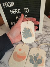 Load image into Gallery viewer, A hand holding one of three pop up sponges with a desert theme. The sponges are compostable.