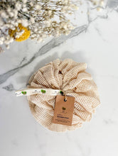 Load image into Gallery viewer, A beige cotton shower pouf with a small loop for hanging. 
