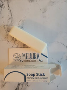Image of soap stick bar next to Meliora box. Soap stick is plain white and rectangular shaped. 