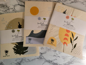 Three packs of reusable Swedish dishcloths on a table, featuring three different designs. 