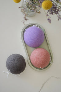 A purple, pink, and black konjac sponge lay in a dish