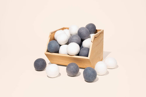 Grey and white, long-lasting wool dryer balls in a basket.