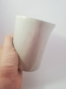 A white hand holds the jug at an angle as if about to pour from it.