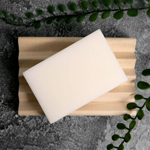 A white conditioner bar rests on a wooden soap holder. Peppermint scent, from Silver Falls Sustainability