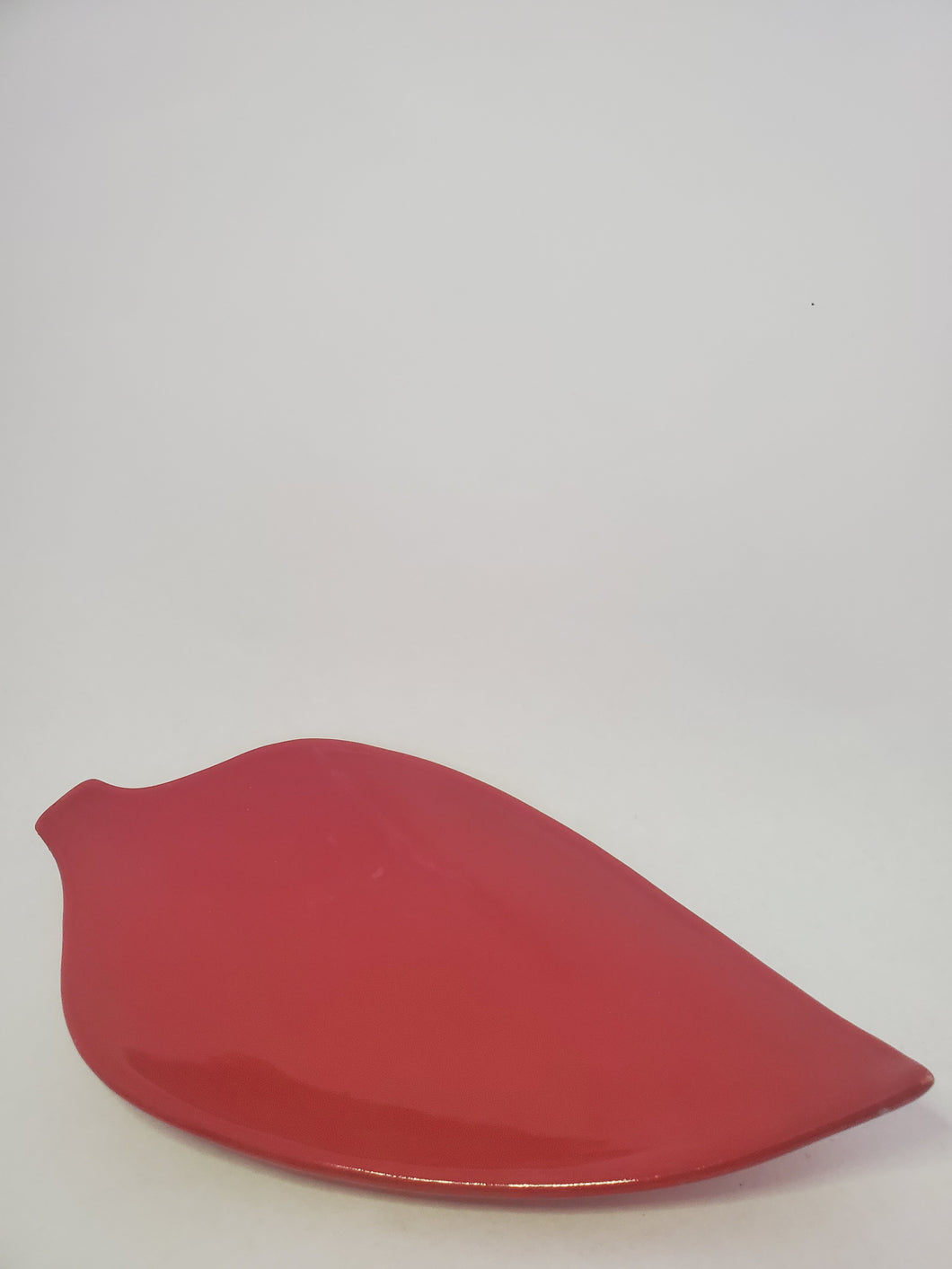 A red, high-gloss leaf shaped plate handmade in Cambodia.