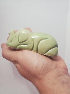 A white hand holds the small, light green elephant incense burner. 